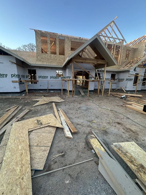 Front of the new home being framed with sheathing and house wrap and steep gable peaks going up