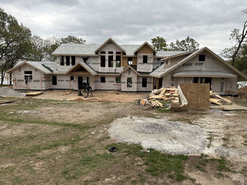 The full new home framed, sheathed, and wrapped tight with the roof decked across every gable